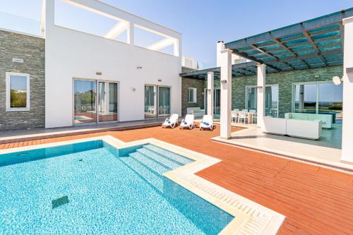 a house with a swimming pool and a patio at Seafront Villa Cecelia by Ruidoso Luxury in Ayia Napa
