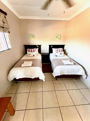 two beds in a room with a tiled floor at Perna Perna Lodge St Lucia in St Lucia