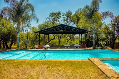 a swimming pool with a pavilion in a yard at Mela Luxury Game Lodge in Pretoria