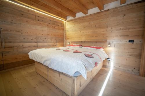 a wooden bedroom with a bed in a log cabin at Appartamento NeveSole in San Vito di Cadore