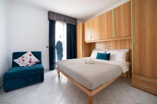 a bedroom with a bed and a blue chair at Casa Merano Residence & Restaurant Bibione Centro in Bibione