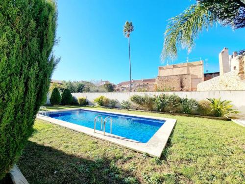 una piscina en un patio con una palmera en Cal Marc - Piso con piscina y terraza, en Ulldecona
