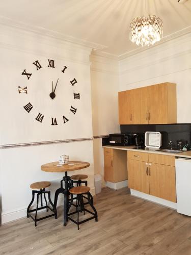 uma cozinha com uma mesa e um relógio na parede em The Cedars Hotel em Lincolnshire