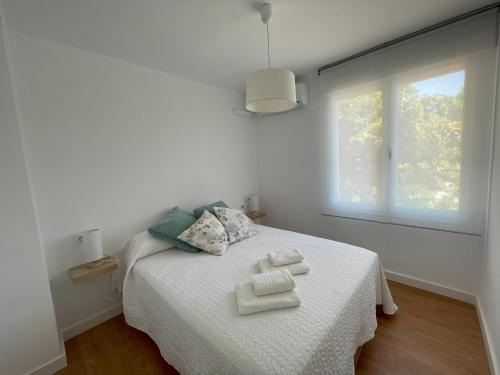 a white bedroom with a bed with two towels on it at Apartamento Colina B 19. in Córdoba