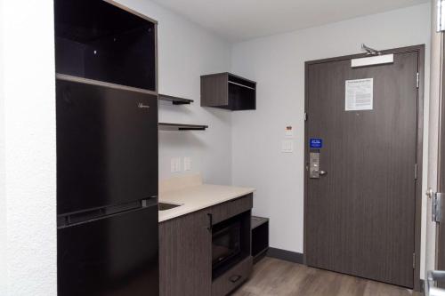 a kitchen with a black refrigerator next to a door at Studio 6 Fort Worth TX Lake Worth in Fort Worth