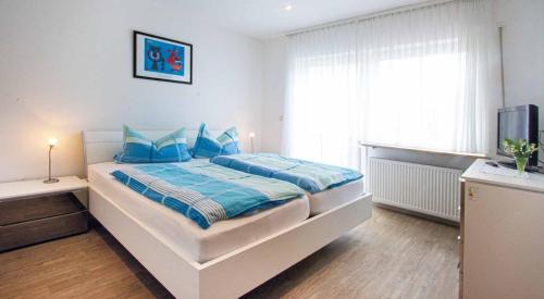 ein Schlafzimmer mit einem Bett mit blauen Kissen und einem TV in der Unterkunft Haus Himmelsbach in Bad Füssing
