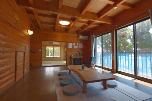 a living room with a table and some windows at ocean resort mint オーシャンビューを満喫!かわいい三角屋根の三階建て貸切別荘 in Shioura