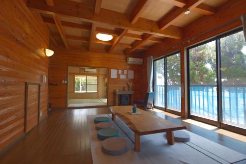 a living room with a table and some windows at ocean resort mint オーシャンビューを満喫!かわいい三角屋根の三階建て貸切別荘 南房総白浜 in Shioura