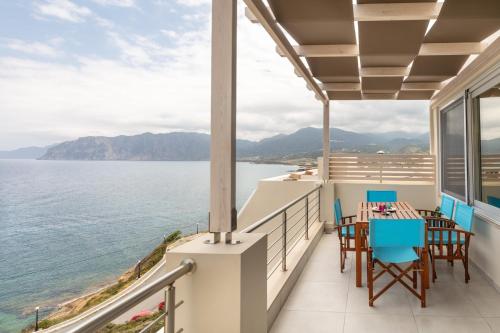 einen Balkon mit Tischen und Stühlen und Blick auf das Wasser in der Unterkunft Serenity apartment Mochlos in Mochlos