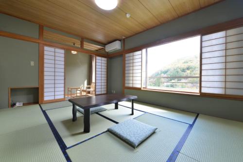 a room with a table in a room with windows at Ooedo Onsen Monogatari Kakeyu in Ueda