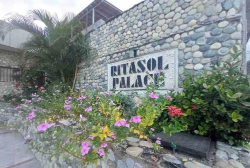 a sign on a stone wall with flowers at Ritasol Palace apartamento de relax frente al mar in Caraballeda