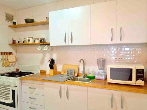 a kitchen with white cabinets and a sink and a microwave at Ritasol Palace apartamento de relax frente al mar in Caraballeda