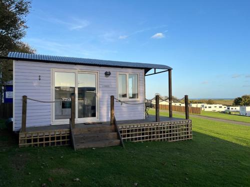 a small house with a porch on a grass field at Pearl Shepherds Hut in Penally
