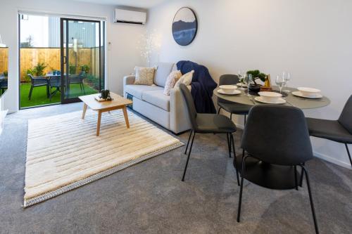 uma sala de estar com um sofá e uma mesa em Stroll through the park 2 bed 2 bath w/carpark em Christchurch