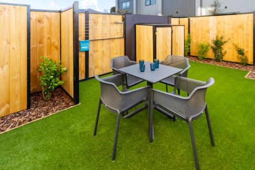 a patio with a table and chairs on grass at Stroll through the park 2 bed 2 bath w/carpark in Christchurch