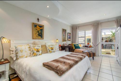 a bedroom with a large bed and a living room at Gordon's Beach Lodge in Gordonʼs Bay
