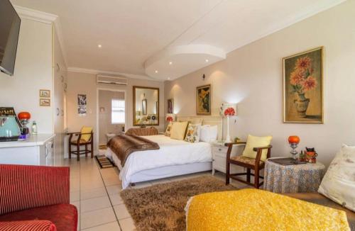 a bedroom with a bed and a living room at Gordon's Beach Lodge in Gordonʼs Bay