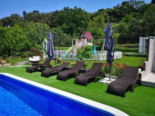 a group of chairs and umbrellas next to a swimming pool at Apartments Villa Subic in Rab