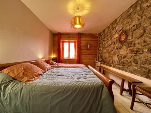 Péreyres的住宿－Gîte de NOE au Ray-pic，一间卧室设有一张床和石墙