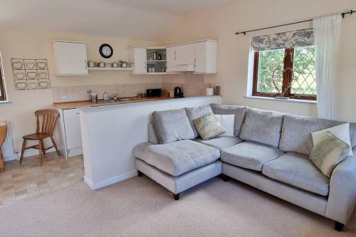 Il comprend un salon avec un canapé et une cuisine. dans l'établissement Little Garden Cottage, Tamar Valley, Cornwall, à Stoke Climsland