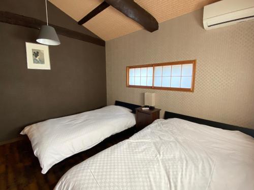 een slaapkamer met 2 bedden en een raam bij Samurai Suite 1 , 15mins from Kyoto Eki , 5 mins to Arashiyama in Kyoto