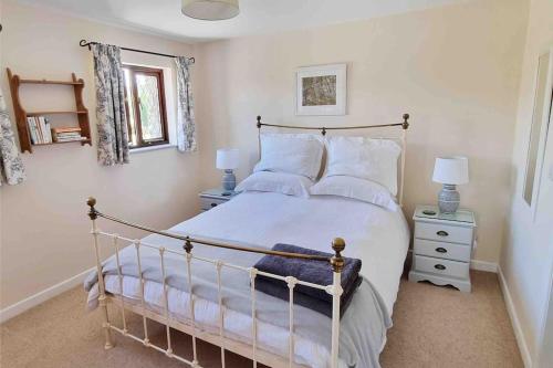 um quarto com uma cama grande com lençóis brancos e almofadas em Little Garden Cottage, Tamar Valley, Cornwall em Stoke Climsland