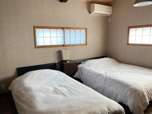 two beds in a bedroom with two windows at Samurai Suite 1 , 15mins from Kyoto Eki , 5 mins to Arashiyama in Kyoto