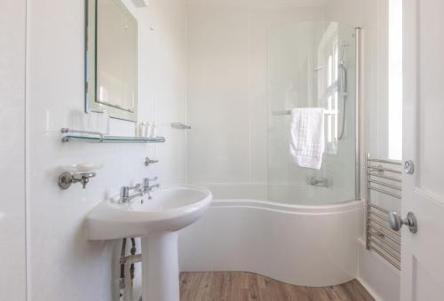 a white bathroom with a sink and a bath tub at Gurnard Cottage in Niton