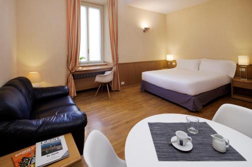 a hotel room with a bed and a couch and a table at Dynasty Suites Downtown Apartments in Turin