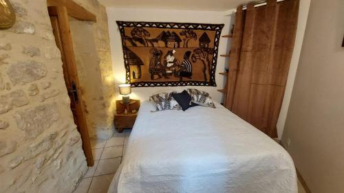 a bedroom with a bed with a picture on the wall at Le Petit Cocon in Vénéjan