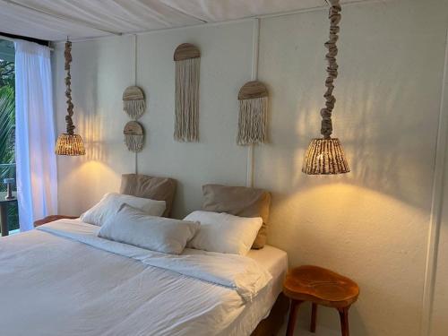 a bedroom with a white bed with two pillows and lights at Boho Beachfront Cottage in Chaloklum