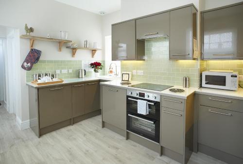a kitchen with gray cabinets and a microwave at Stella in Marcross