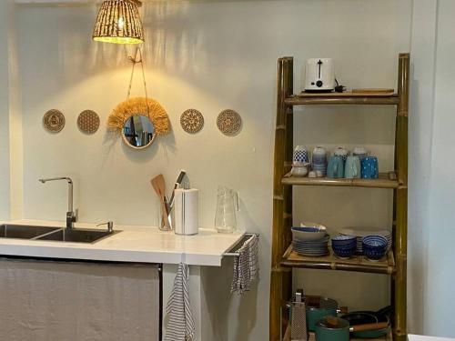 a kitchen with a sink and a counter with shelves at Boho Beachfront Cottage in Chaloklum