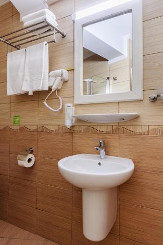 a bathroom with a sink and a mirror and towels at Hotel Central - Baile Olanesti in Băile Olăneşti