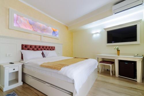 ein Schlafzimmer mit einem großen Bett und einem TV in der Unterkunft Hotel Central - Baile Olanesti in Băile Olăneşti