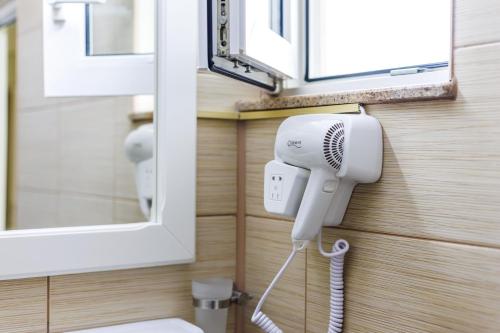 a bathroom with a hair dryer and a mirror at Hotel Central - Baile Olanesti in Băile Olăneşti