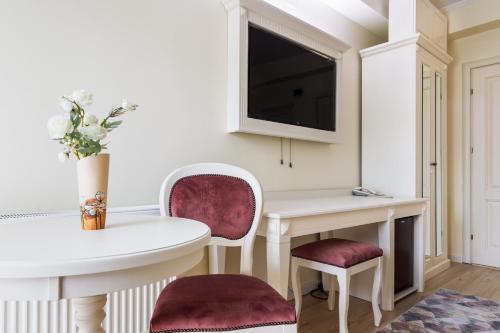 a living room with a table and chairs and a tv at Hotel Central - Baile Olanesti in Băile Olăneşti