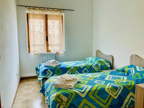 2 letti in una camera con lenzuola blu e verdi di Vivo il Centro a Praia a Mare