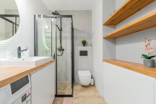 a bathroom with a shower and a sink and a toilet at Apartamenty Mierzeja NCNK Baltic Garden Sztutowo in Sztutowo