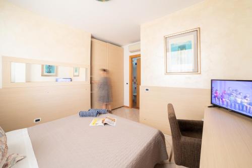 a small room with a bed and a tv at Casa Merano Residence & Restaurant Bibione Centro in Bibione