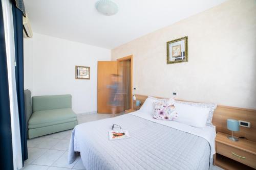 a hotel room with a bed and a chair at Casa Merano Residence & Restaurant Bibione Centro in Bibione