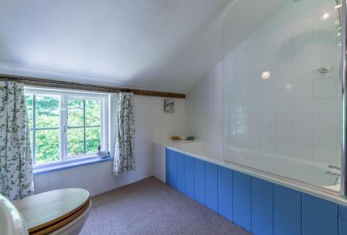 a bathroom with a tub and a window at Holly Cottage in Huntingfield