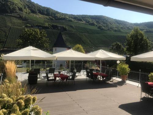 a patio with tables and chairs and white umbrellas at Gästehaus & Weingut Clüsserath-Weiler in Trittenheim