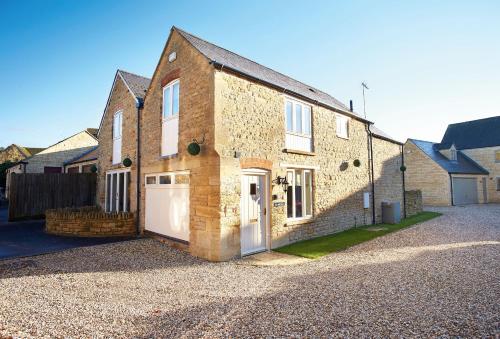 a brick house with a garage on a gravel driveway at The Old Bakery in Kingham