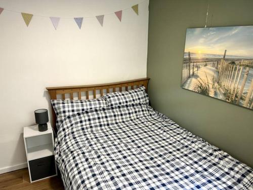 a bedroom with a bed with a checkered pillow and a painting at Sea Valley 33 Bideford Bay Holiday Park in Bideford