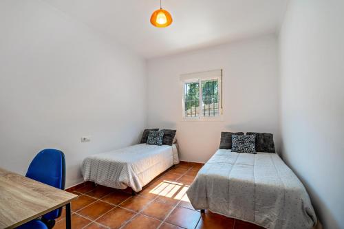 een kamer met 2 bedden, een tafel en een raam bij Villa Jero in Chiclana de la Frontera