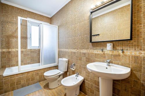 een badkamer met een wastafel, een toilet en een spiegel bij Villa Jero in Chiclana de la Frontera