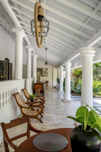 a porch with chairs and tables and a chandelier at The Well House Galle Sri Lanka in Unawatuna