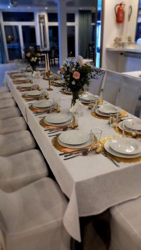 a long table with chairs and plates and flowers on it at Hotel i Restauracja 13 Smaków in Częstochowa
