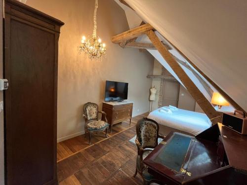 a bedroom with a bed and a desk and a tv at Charnay Plaisance, piscine, les chambres du chocolatier Daniel Mercier in Vierzon
